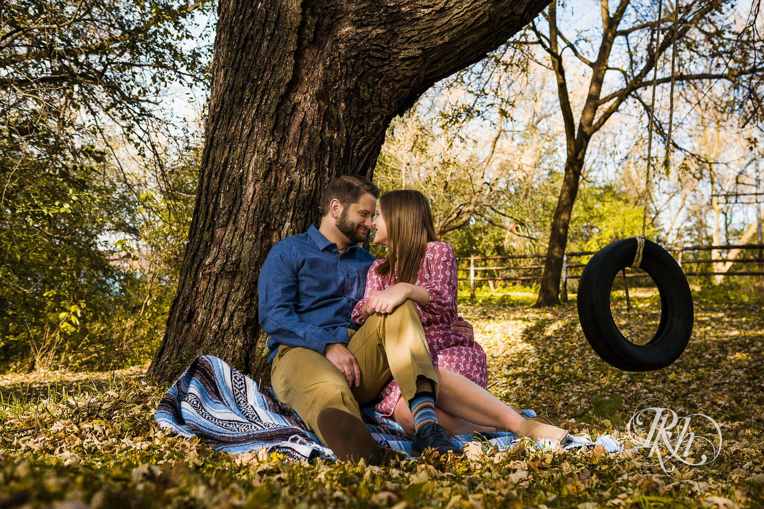 Man and woman kiss in leaves during engagement photography session at home in Annandale, Minnesota.
