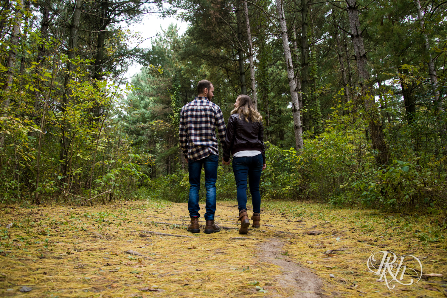 Man in flannel and woman in yellow scarf walk in woods at Lebanon Hills Regional Park in Eagan, Minnesota.