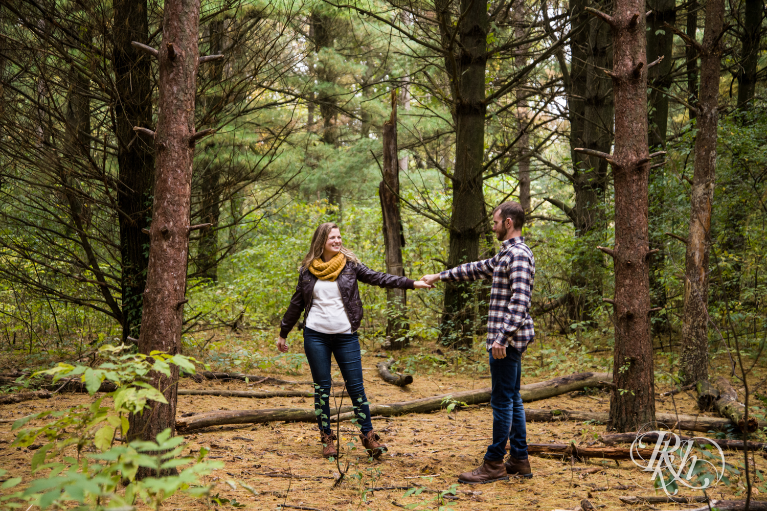 Man in flannel and woman in yellow scarf dance in woods at Lebanon Hills Regional Park in Eagan, Minnesota.
