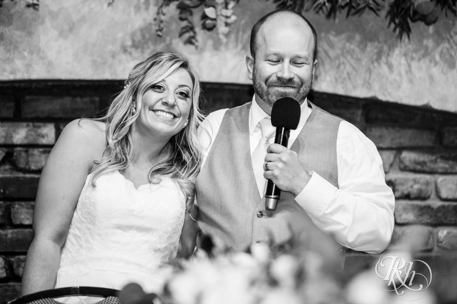 Bride and groom smile during wedding speeches at the Minnesota Boat Club on Raspberry Island in Saint Paul, Minnesota.