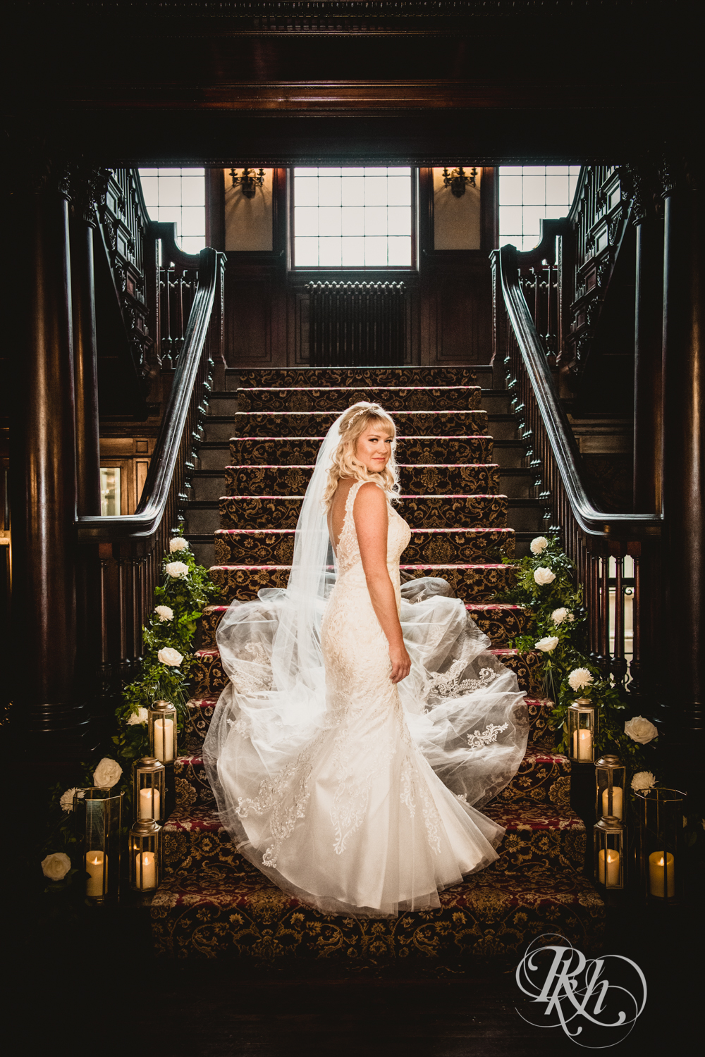 Bride standing on grand staircase with candles at the Semple Mansion in Minneapolis, Minnesota.