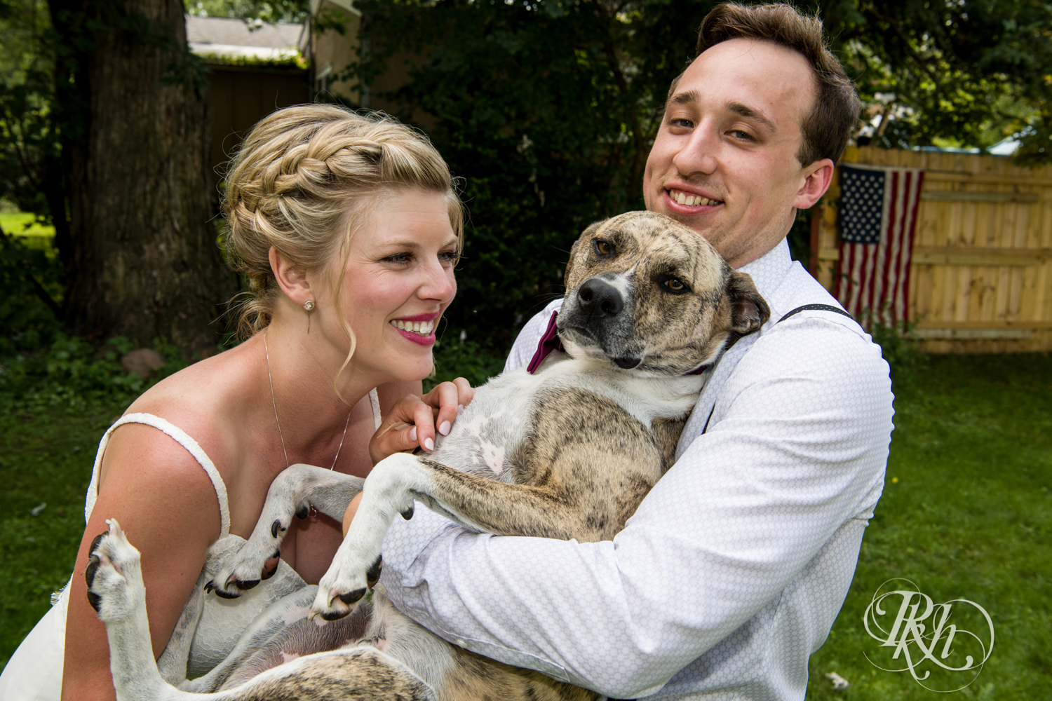 Bride and groom play with their dog at home in Golden Valley, Minnesota.