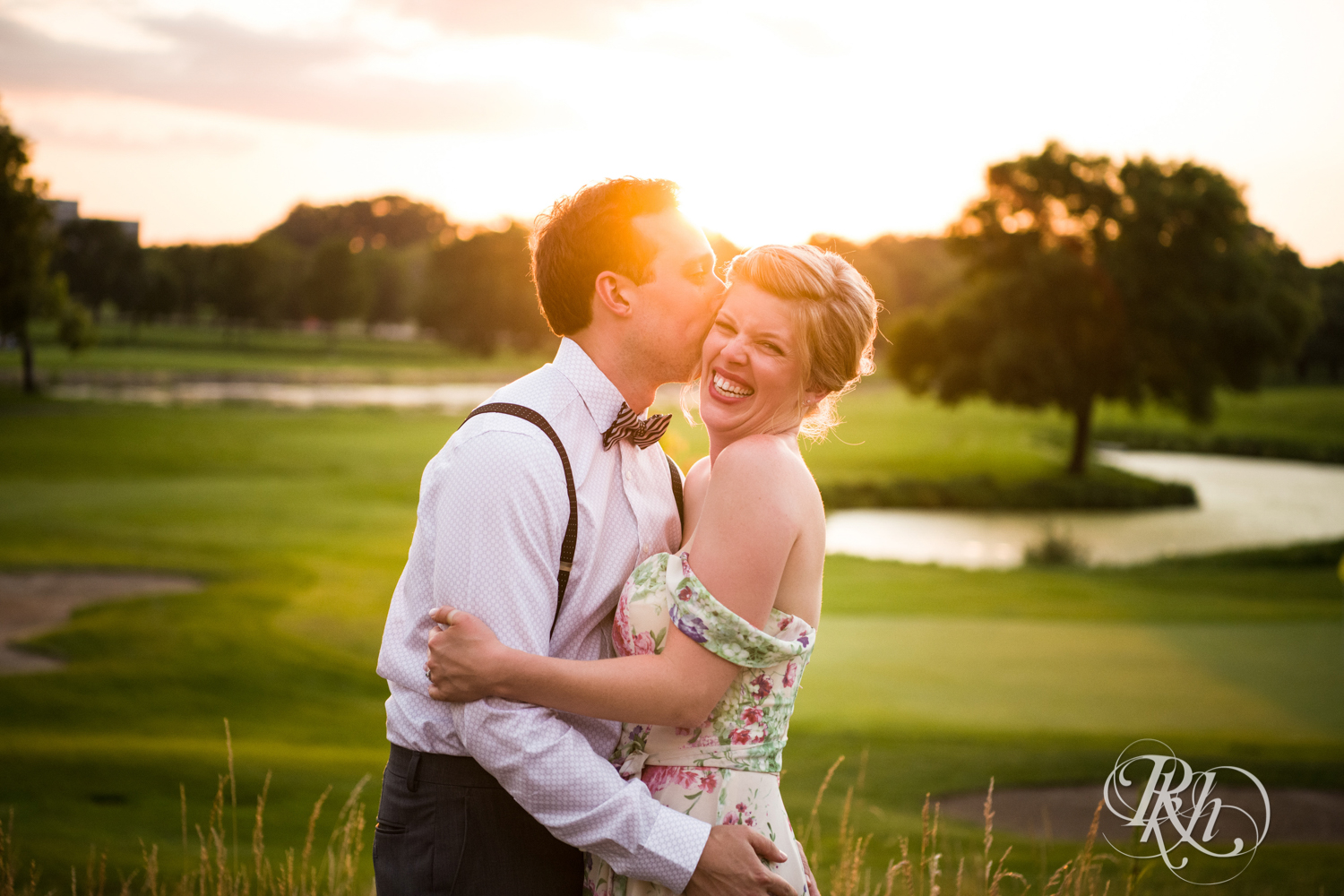 Bride and groom laugh and kiss at sunset at Brookview Golf Course in Golden Valley, Minnesota.
