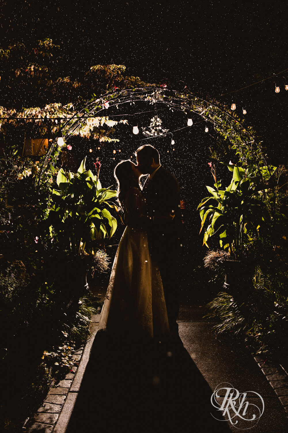 Bride and groom kiss in falling snow at night at Kellerman's Event Center in White Bear Lake, Minnesota.