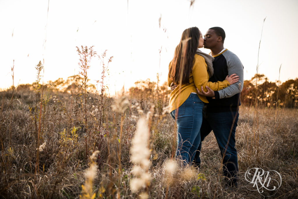 Black man and woman kiss in field during sunset at Lebanon Hills Regional Park in Eagan, Minnesota.