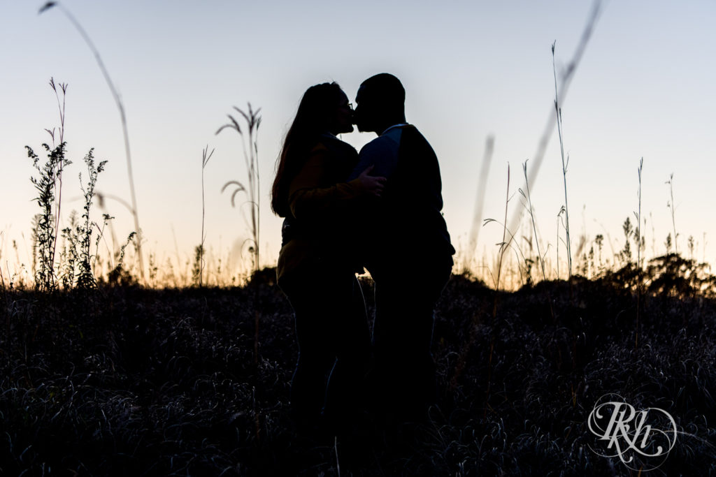 Black man and woman kiss in field during sunset at Lebanon Hills Regional Park in Eagan, Minnesota.