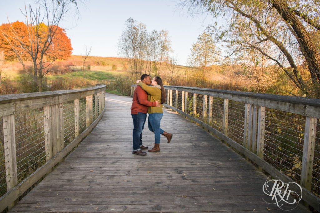 Black man and woman kiss on bridge during sunset at Lebanon Hills Regional Park in Eagan, Minnesota.