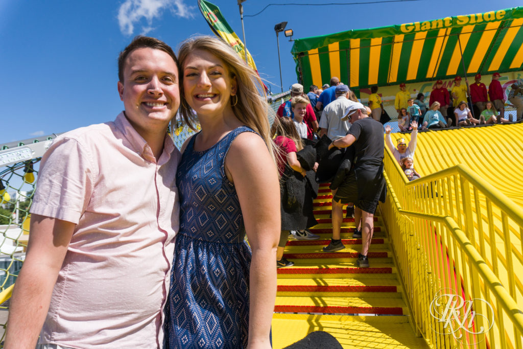 Man and woman in blue dress standing in front of the giant slide at the Minnesota State Fair.