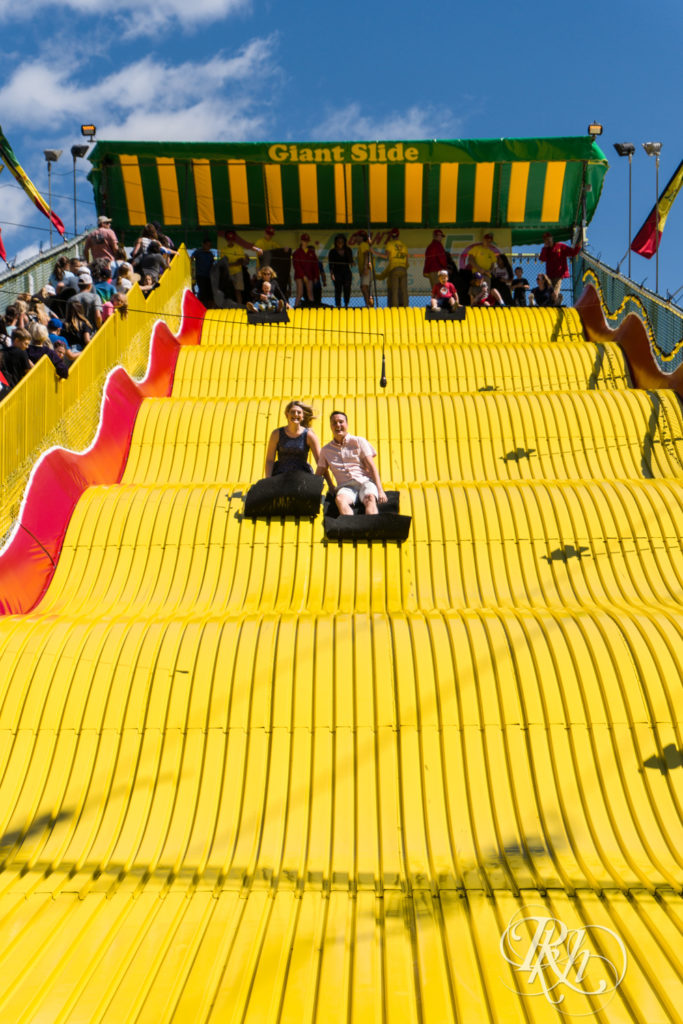 Man and woman in blue dress riding down the giant slide at the Minnesota State Fair.