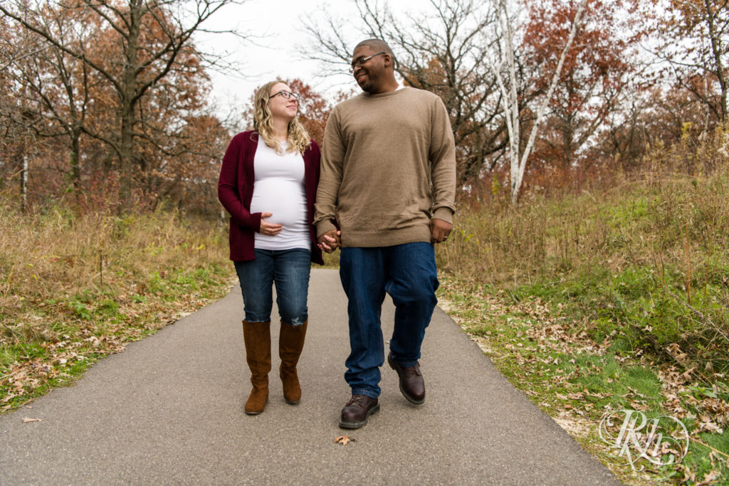 Black man and white woman biracial couple smile pregnant in Lebanon Hills Regional Park in Eagan, Minnesota. 