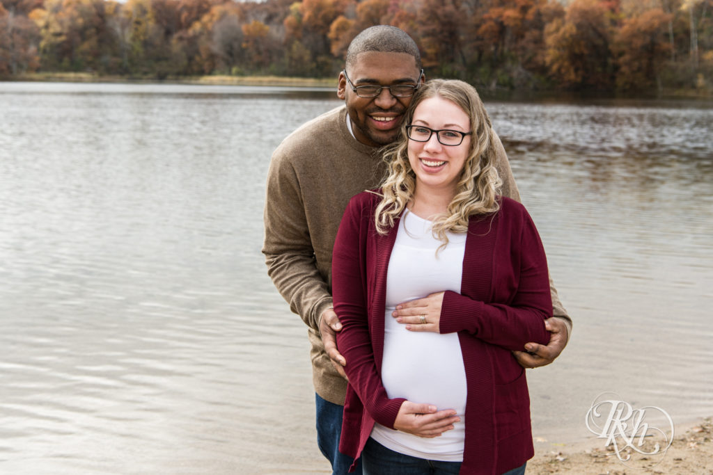 Black man and white woman biracial couple smile pregnant in Lebanon Hills Regional Park in Eagan, Minnesota. 