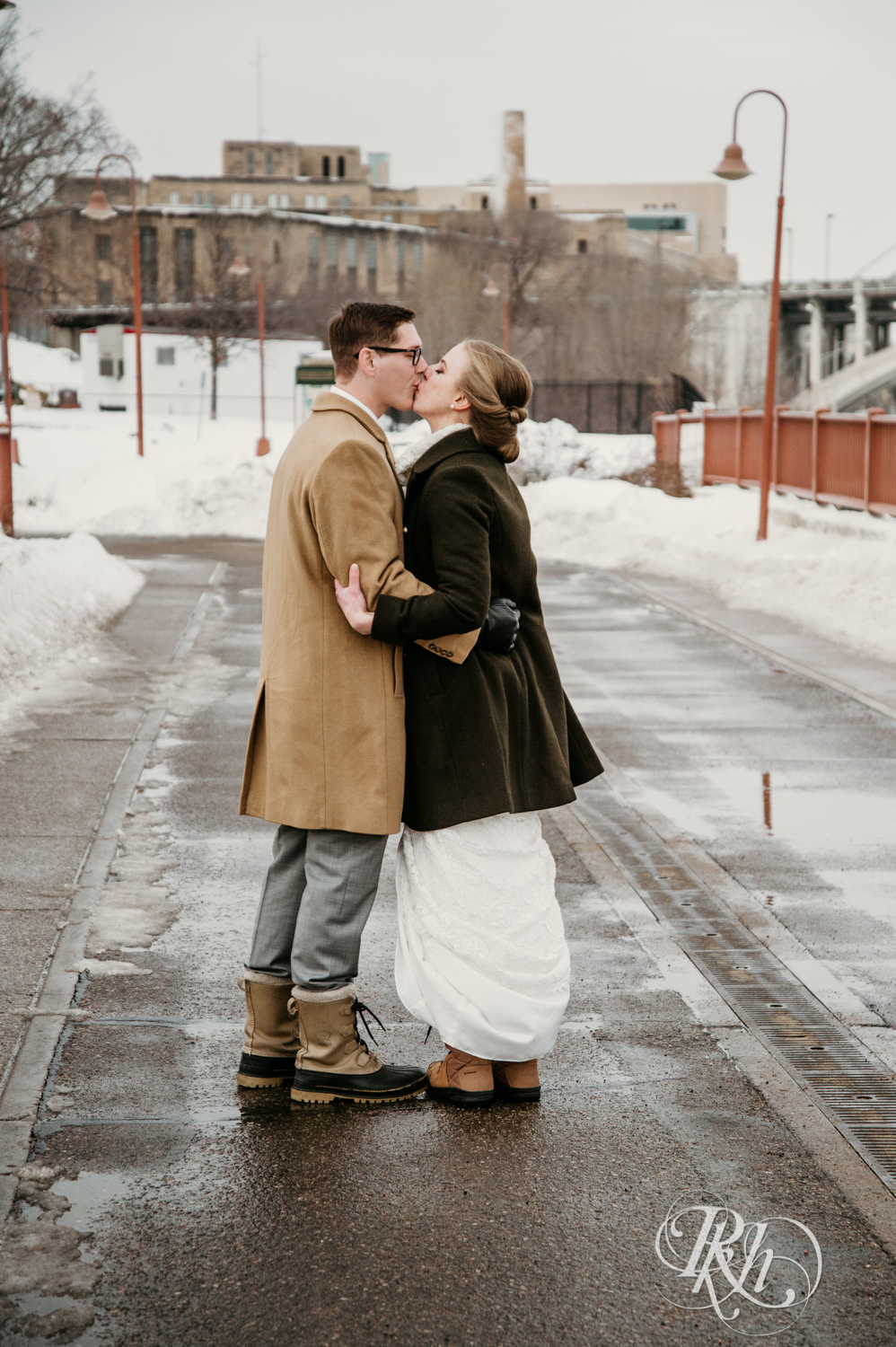 Bride and kiss on snow covered Stone Arch Bridge in Minneapolis, Minnesota.