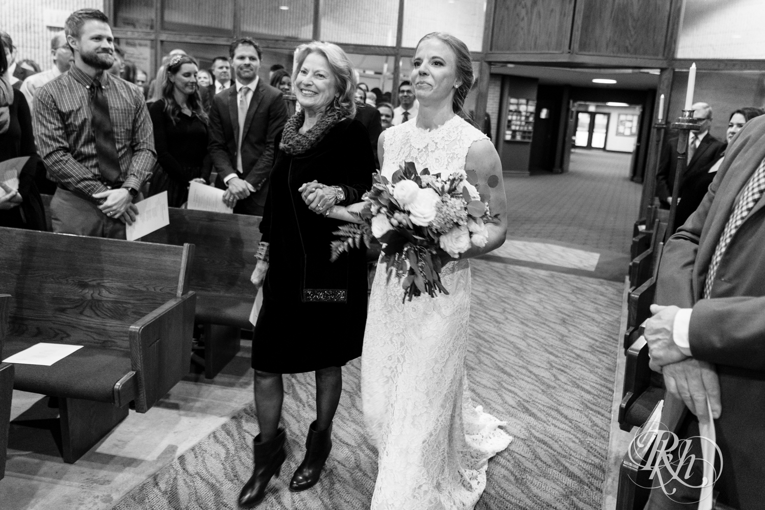 Bride walks down the aisle with her mom in church wedding ceremony in Golden Valley, Minnesota.