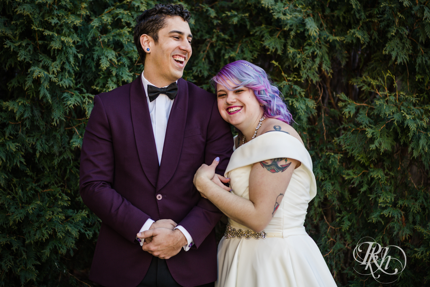 Bride with rainbow hair and groom in maroon suit laugh at the Saint Paul Hotel in Saint Paul, Minnesota.