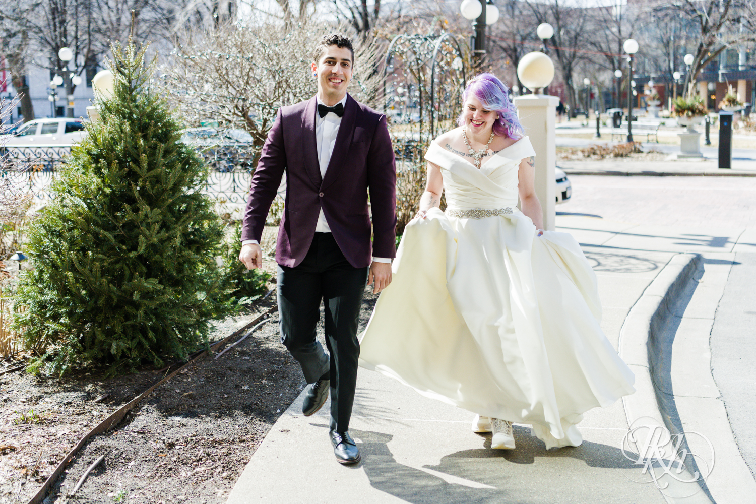 Bride with rainbow hair and groom in maroon suit smile at the Saint Paul Hotel in Saint Paul, Minnesota.