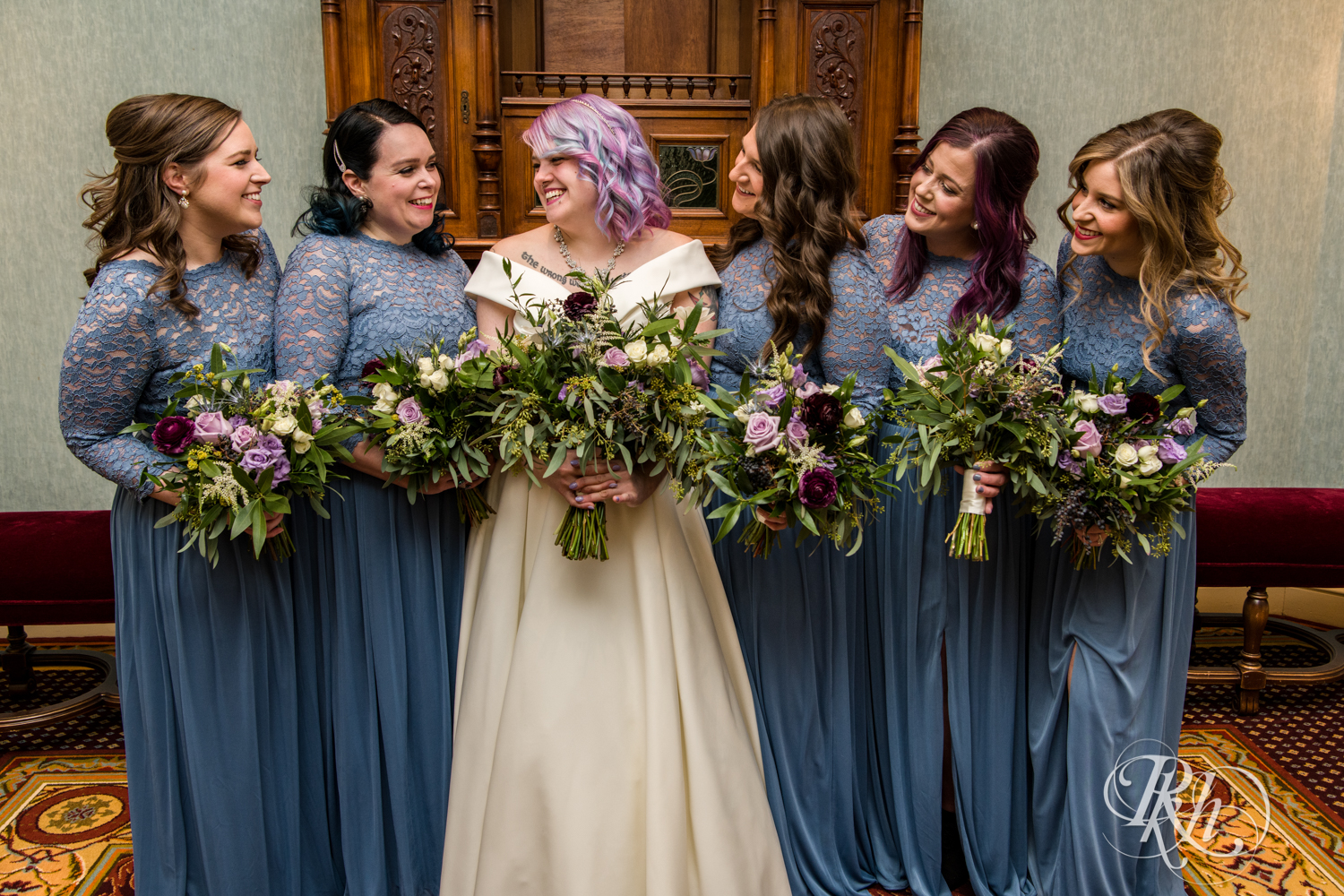 Wedding party in long sleeve blue dressess smile at the Saint Paul Hotel in Saint Paul, Minnesota.