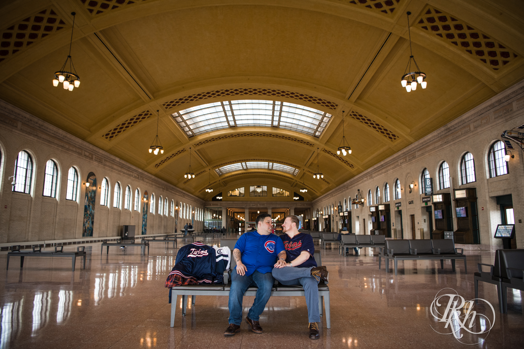 Two gay men in baseball jerseys smile in Union Depot in Saint Paul, Minnesota.