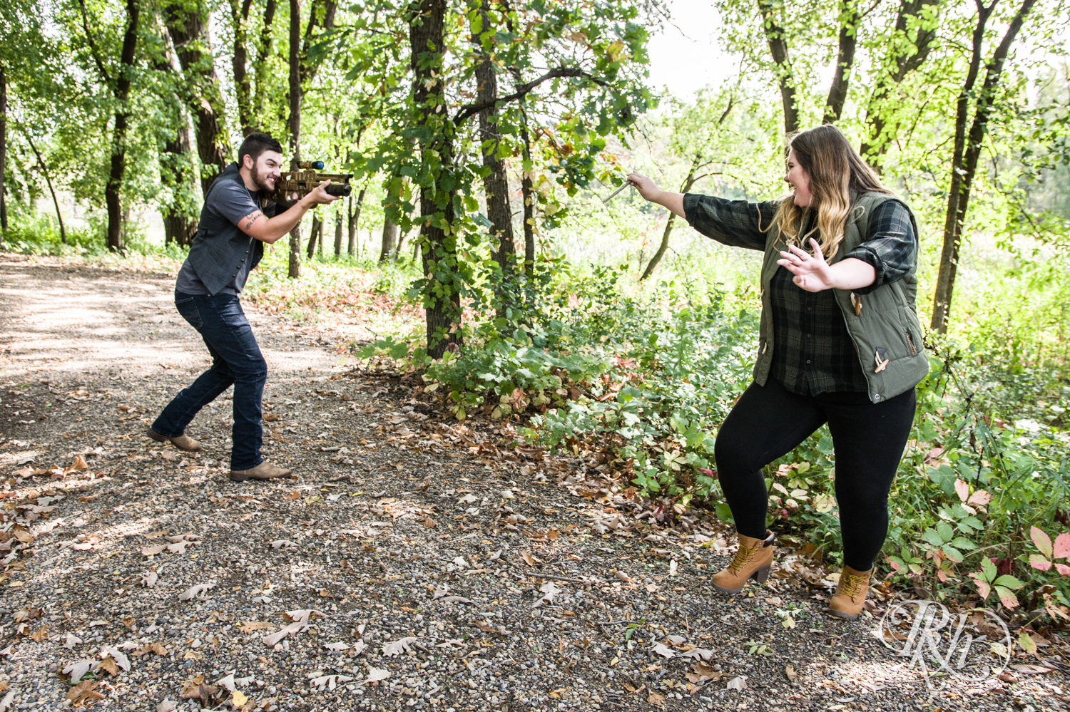 Man with XBox gun and woman with Harry Potter wand battling during engagement session in woods in Plymouth, Minnesota.