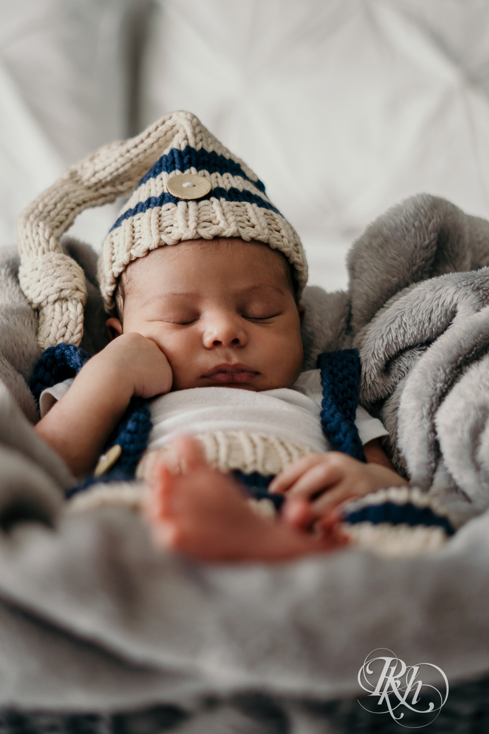 Biracial baby wearing knit cap sleeps on a bed in Burnsville, Minnesota at home.