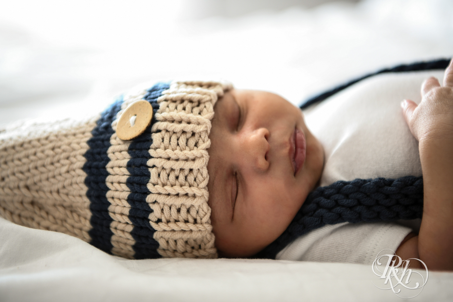 Biracial baby wearing knit cap sleeps on a bed in Burnsville, Minnesota at home.