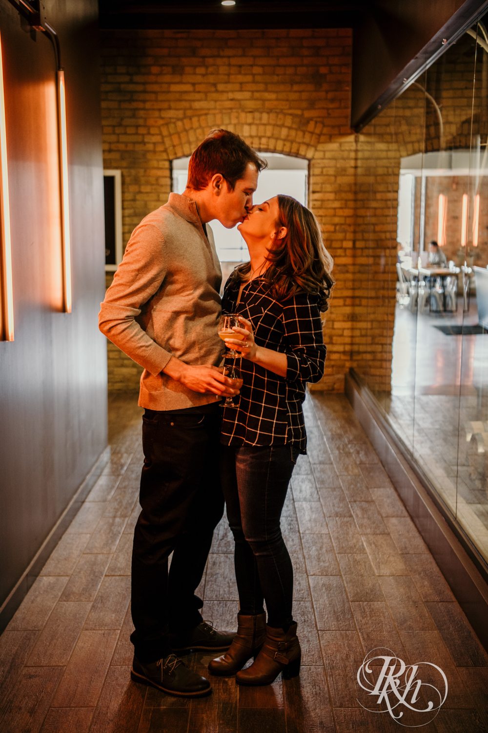 Man and woman in flannel and jeans kiss in hallway at Headflyer Brewery in Minneapolis, Minnesota.