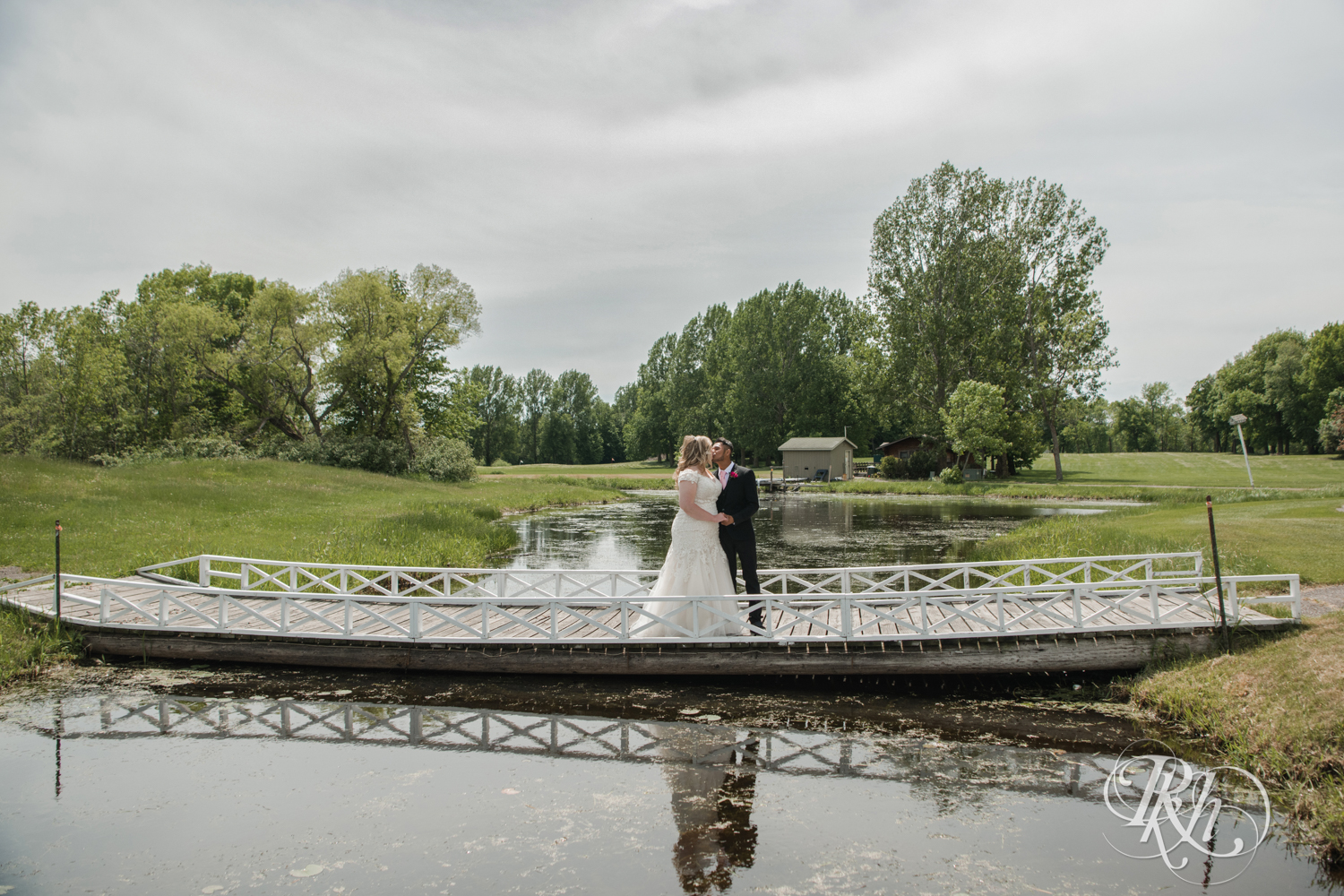 Bride and groom kiss on a bridge over a pond at Izatys Resort in Onamia, Minnesota.