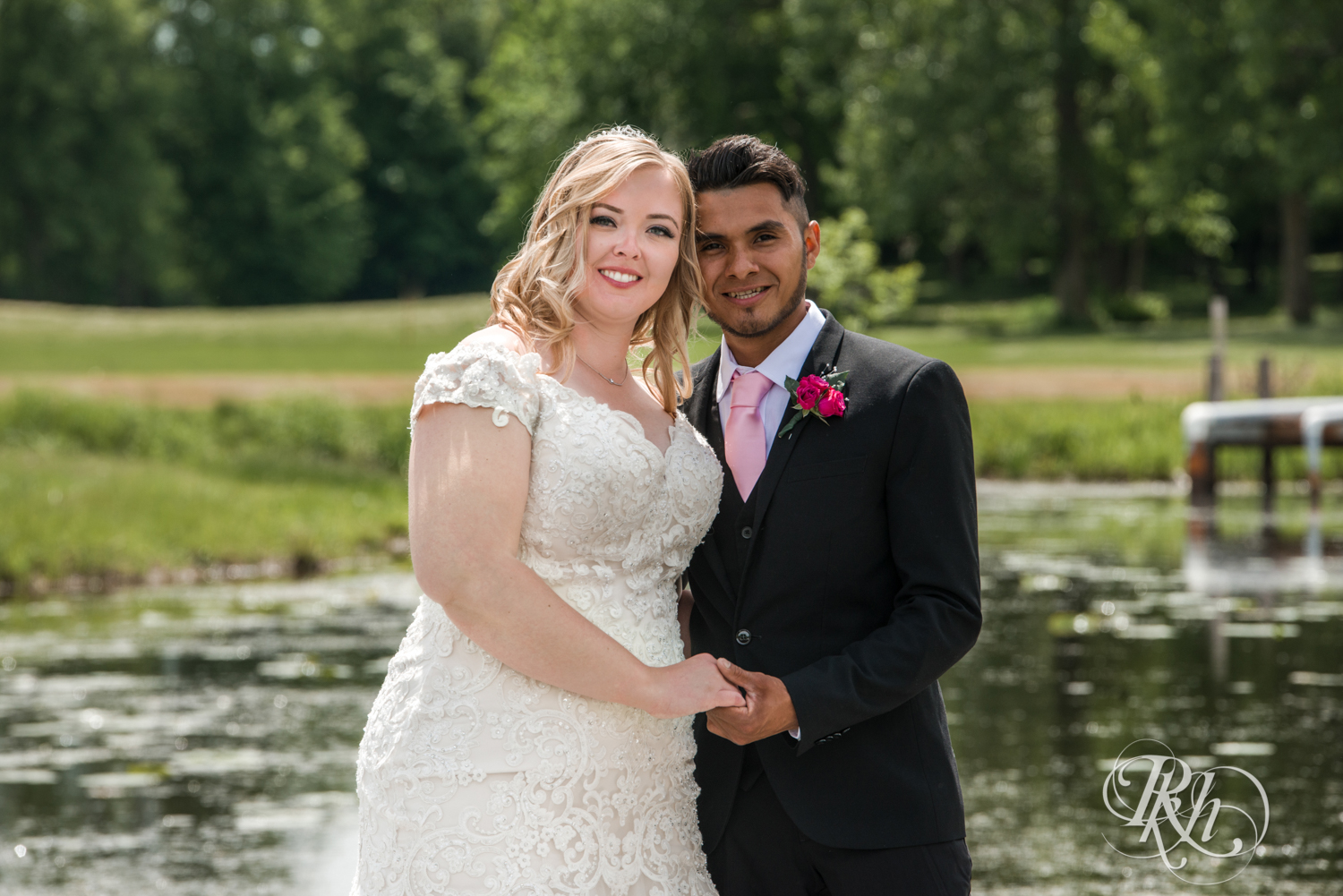 Bride and groom smile on a bridge over a pond at Izatys Resort in Onamia, Minnesota.