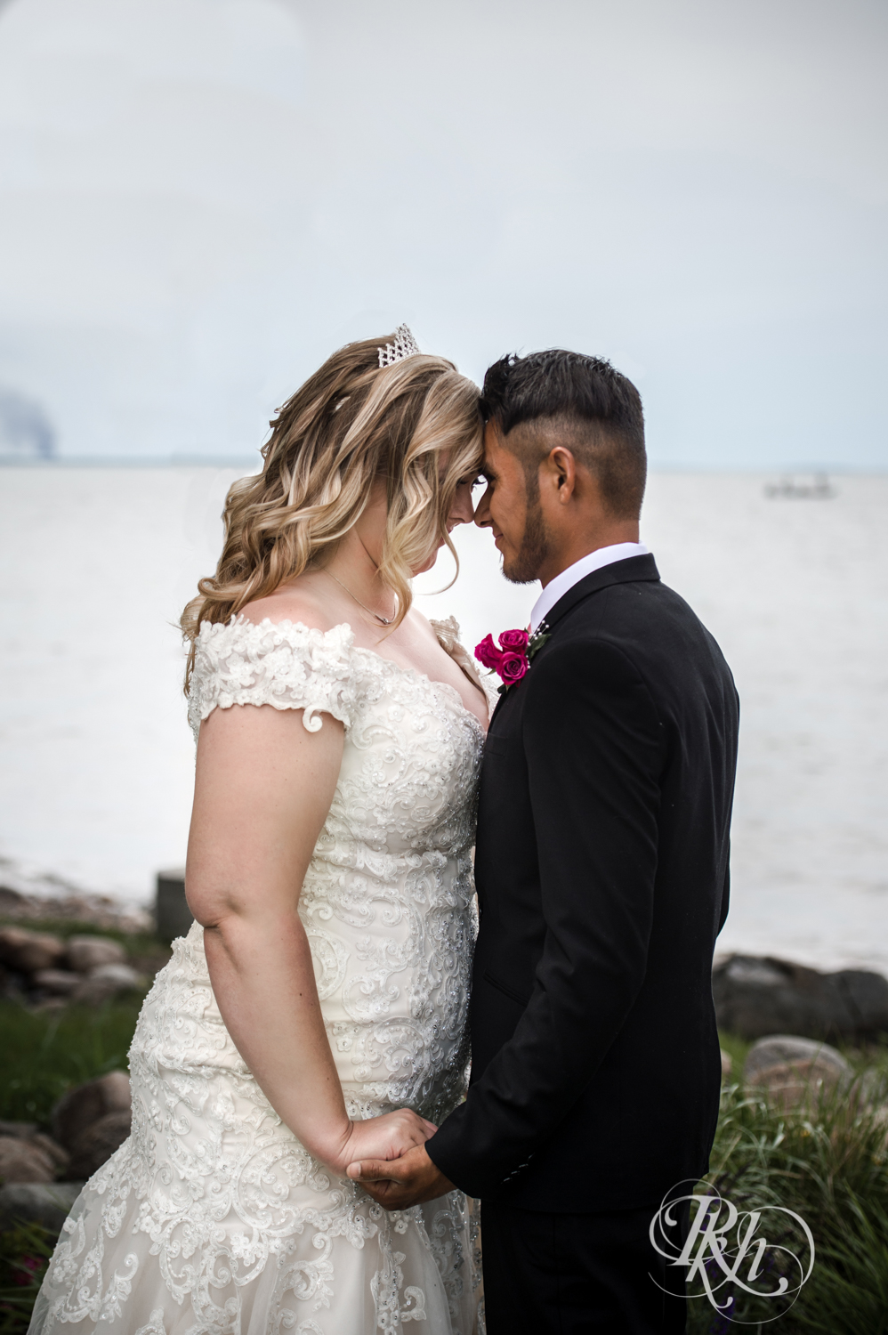 Bride and groom smile in front of Lake Mille Lacs at Izatys Resort in Onamia, Minnesota.