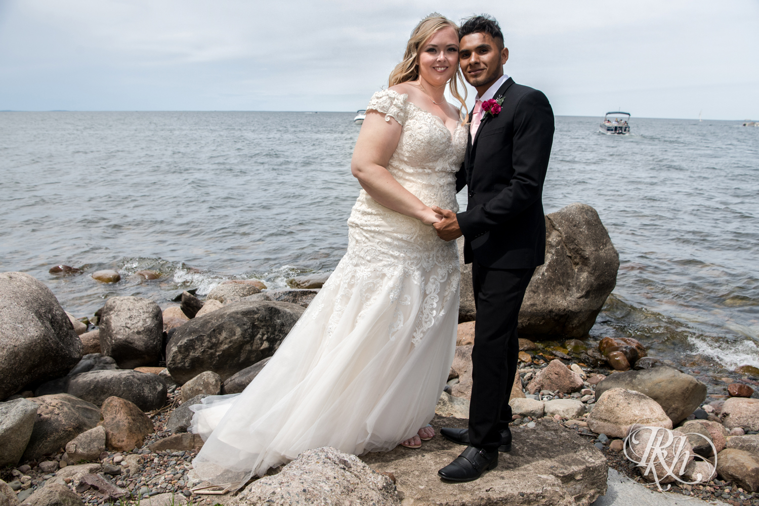 Bride and groom smile in front of Lake Mille Lacs at Izatys Resort in Onamia, Minnesota.