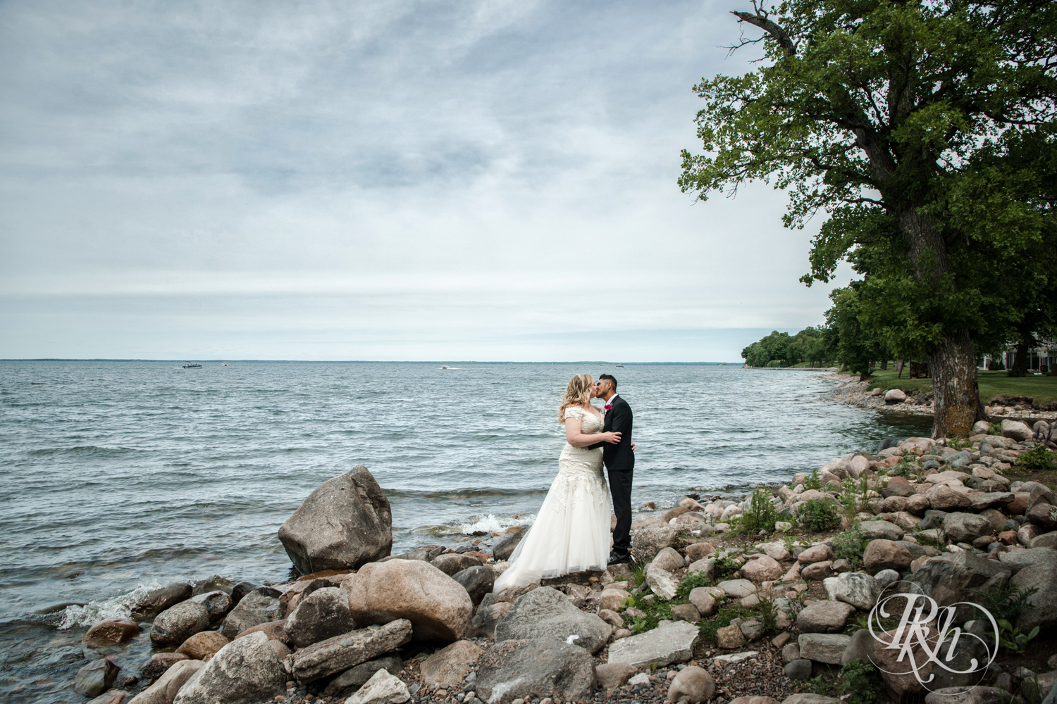 Bride and groom kiss in front of Lake Mille Lacs at Izatys Resort in Onamia, Minnesota.