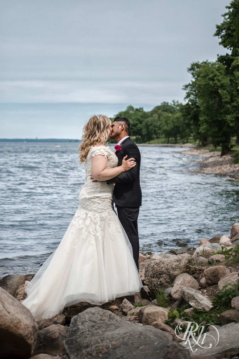 Bride and groom kiss in front of Lake Mille Lacs at Izatys Resort in Onamia, Minnesota.