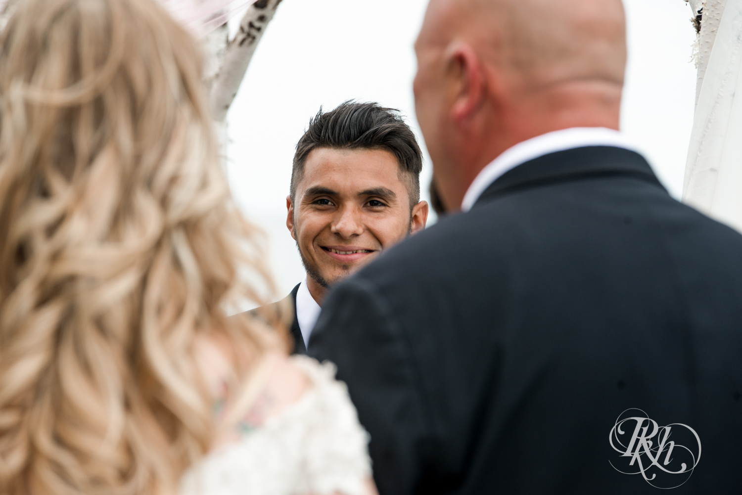 Groom sees bride walk down the aisle with dad at wedding ceremony at Izatys Resort in Onamia, Minnesota.