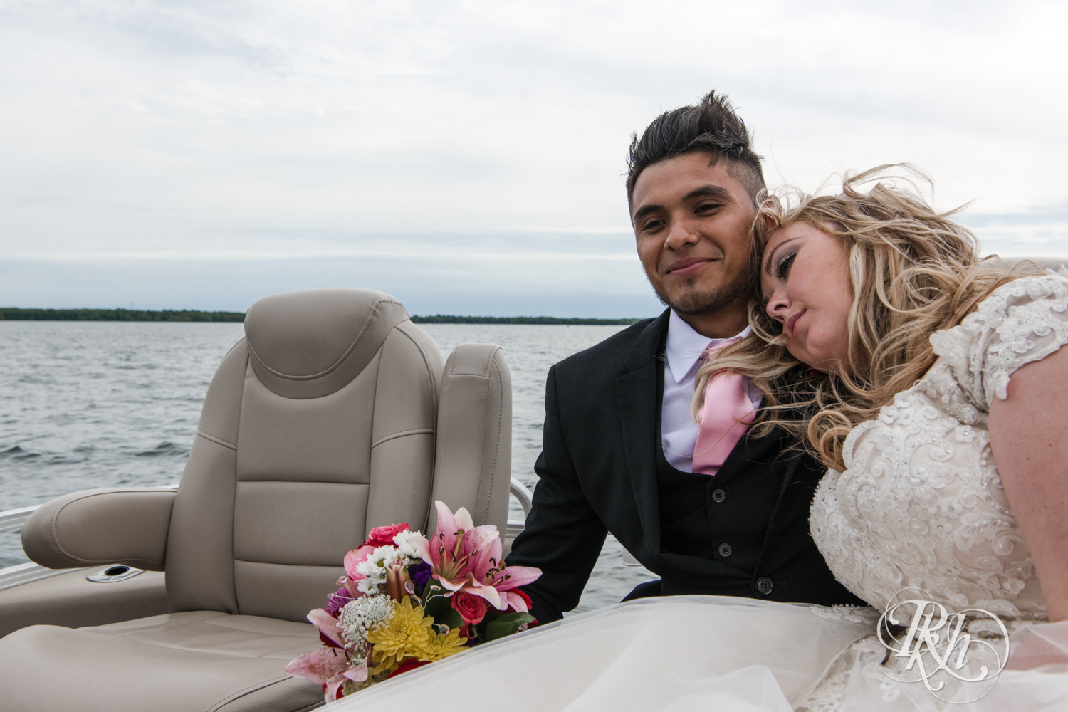 Bride and groom cuddle on boat on Lake Mille Lacs at Izatys Resort in Onamia, Minnesota.