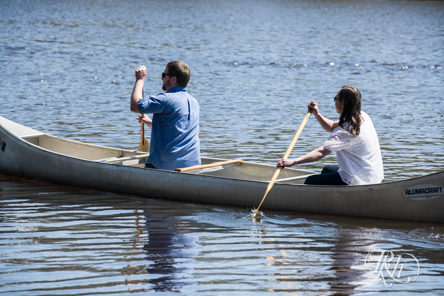 Man and woman row canoe in their engagement session in Taylor's Falls, Minnesota.