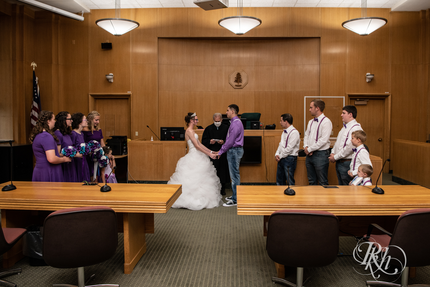 Bride and groom hold hands during wedding ceremony in Chippewa Falls Courthouse in Chippewa Falls, Wisconsin. 