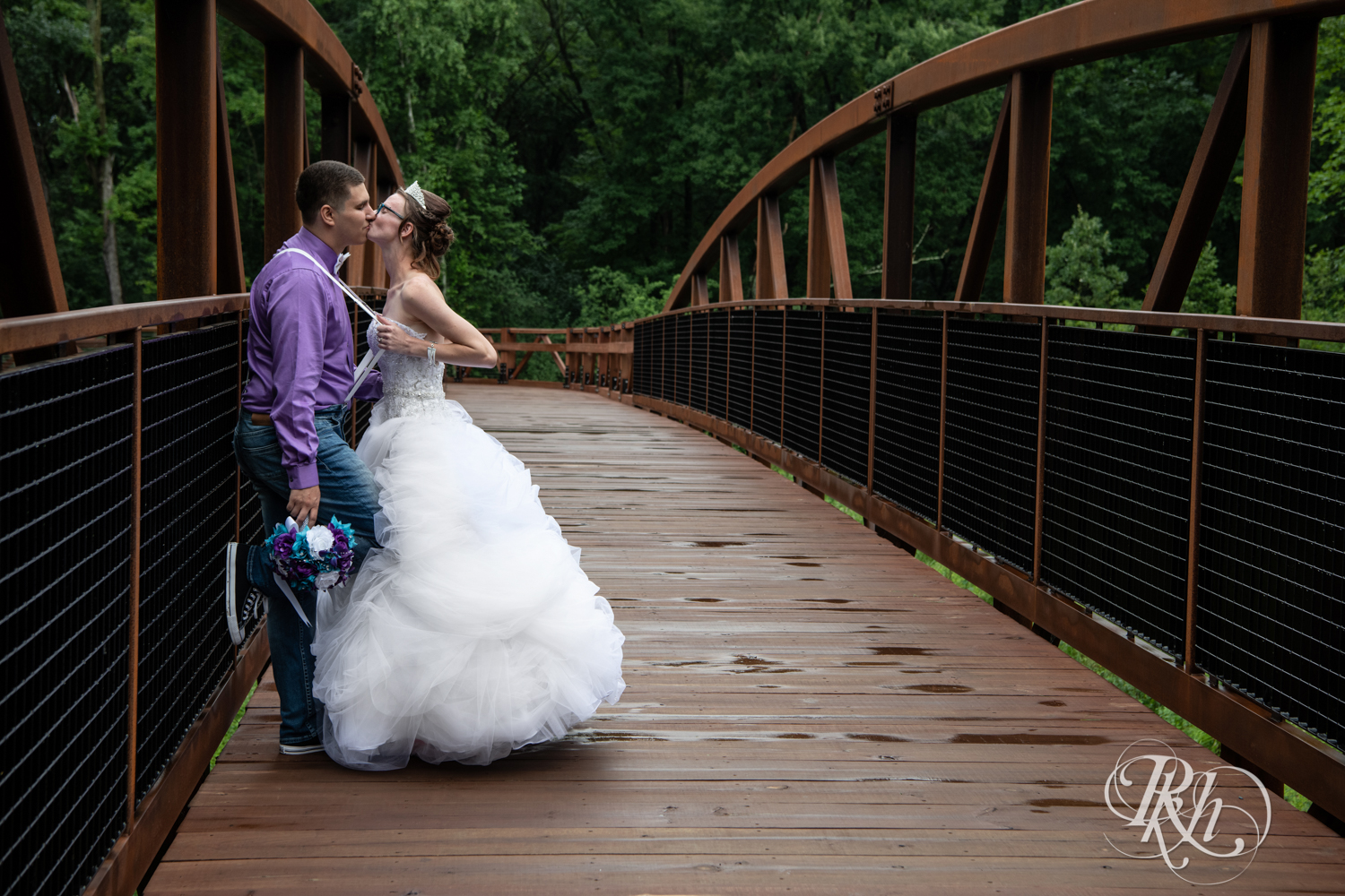 Bride and groom kiss on a bridge in the rain in Irvine Park in Chippewa Falls, Wisconsin. 