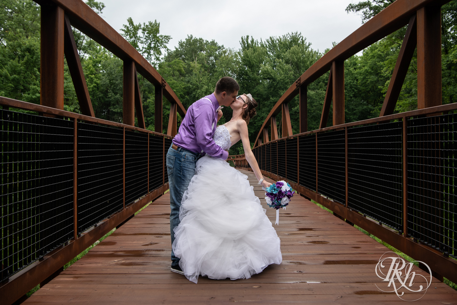 Bride and groom kiss on a bridge in the rain in Irvine Park in Chippewa Falls, Wisconsin. 
