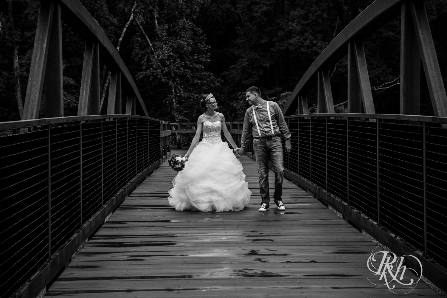 Bride and groom walk on a bridge in the rain in Irvine Park in Chippewa Falls, Wisconsin. 
