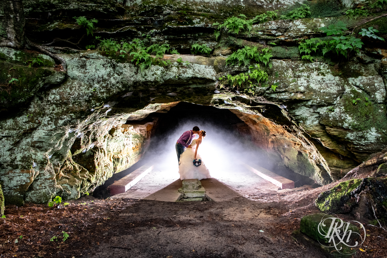 Bride and groom kiss in an abandoned cave in the rain in Irvine Park in Chippewa Falls, Wisconsin. 