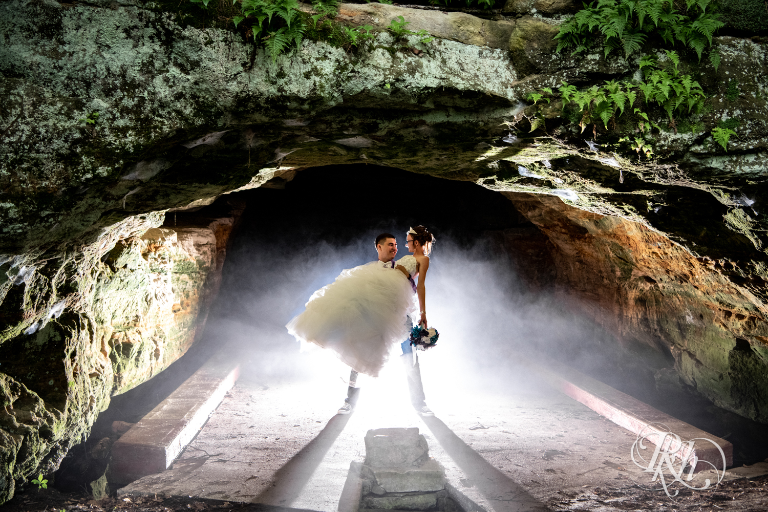 Bride and groom kiss in an abandoned cave in the rain in Irvine Park in Chippewa Falls, Wisconsin. 