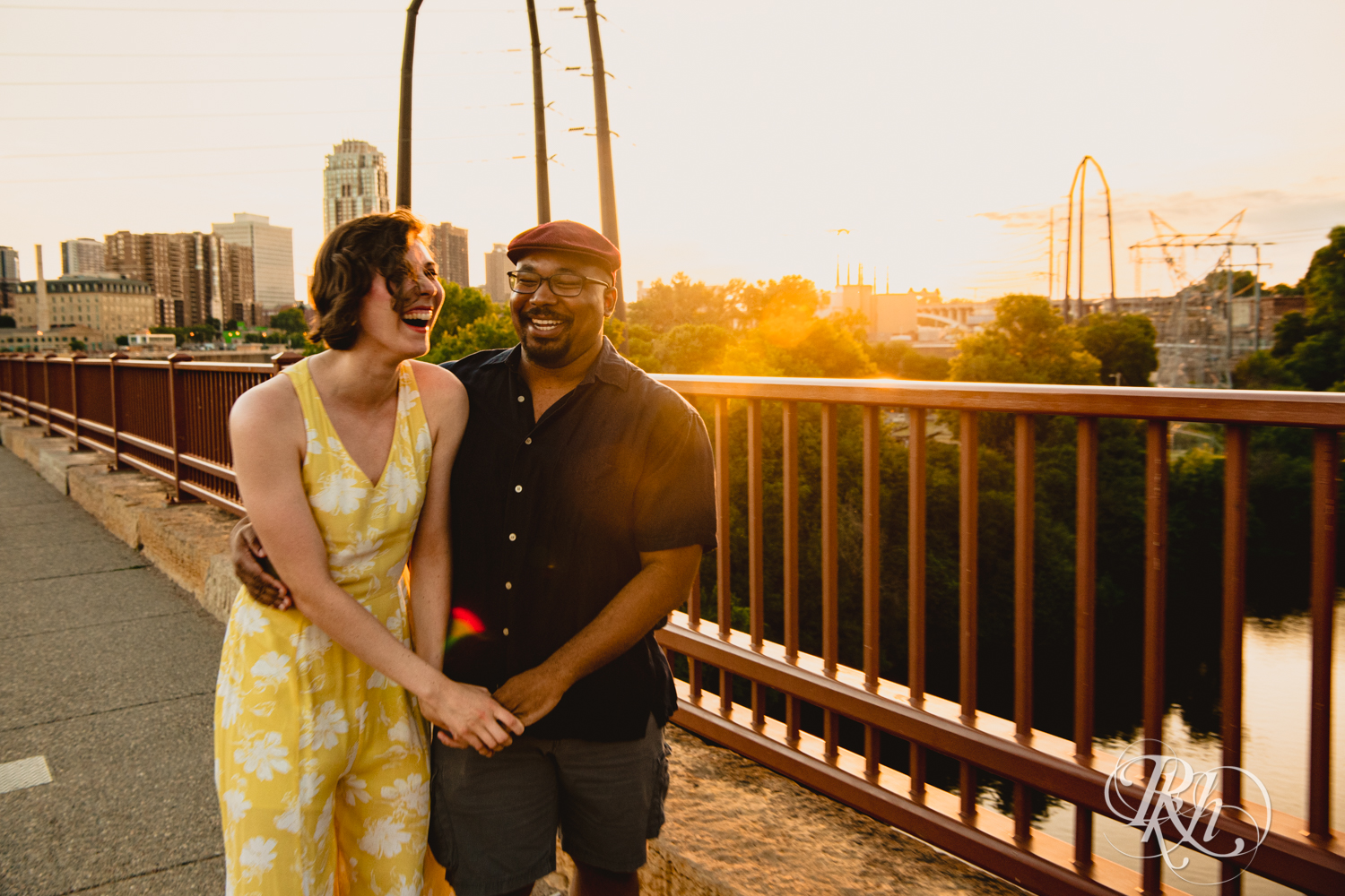 Black man and woman laugh at sunset on Stone Arch Bridge in Minneapolis, Minnesota.