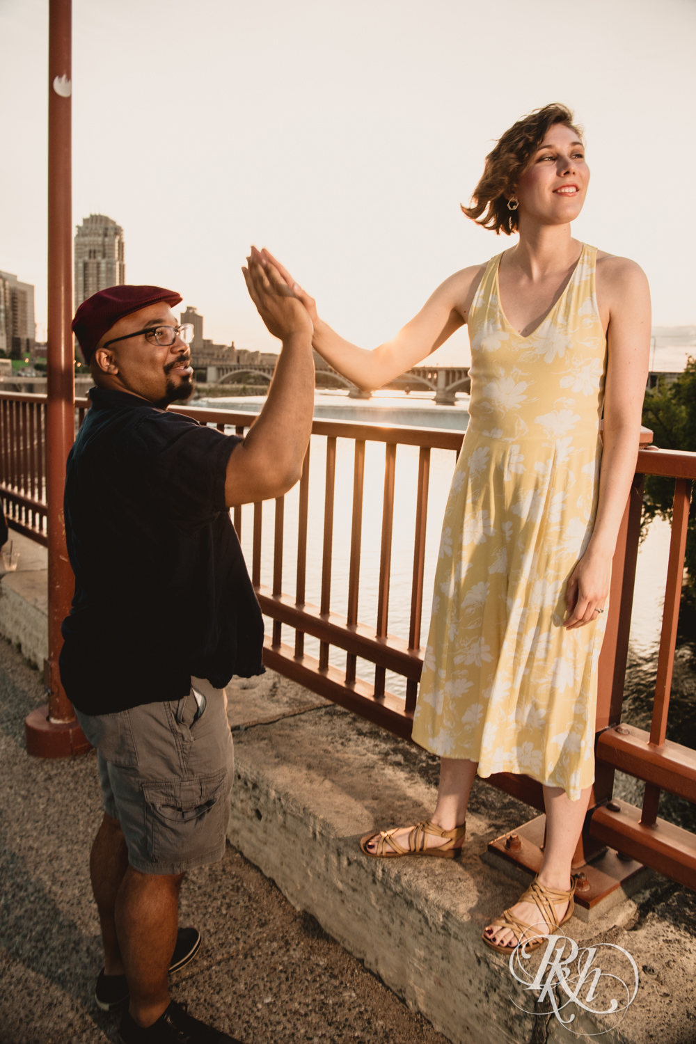 Black man and woman high five at sunset on Stone Arch Bridge in Minneapolis, Minnesota.