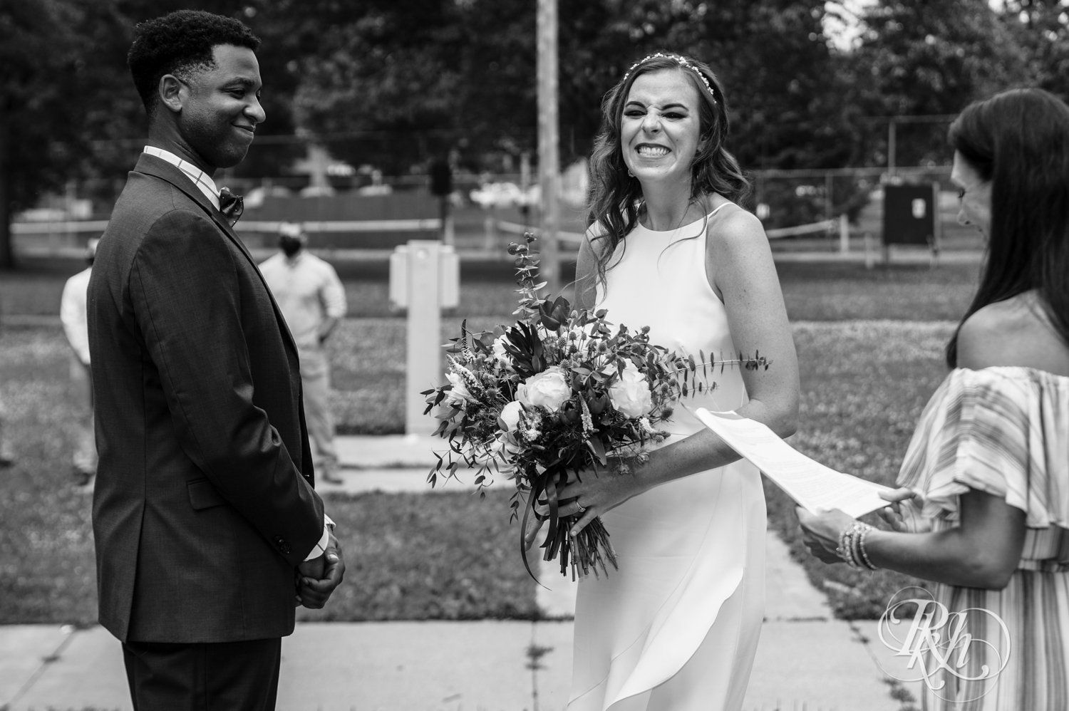 Black man and woman biracial couple hold hands during wedding ceremony in Loring Park in Minneapolis, Minnesota.