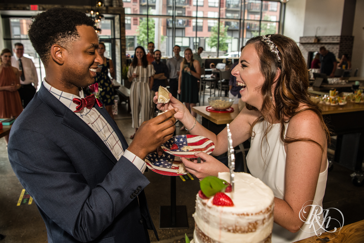 Black man and woman biracial couple eat wedding cake at wedding reception in Minneapolis, Minnesota.