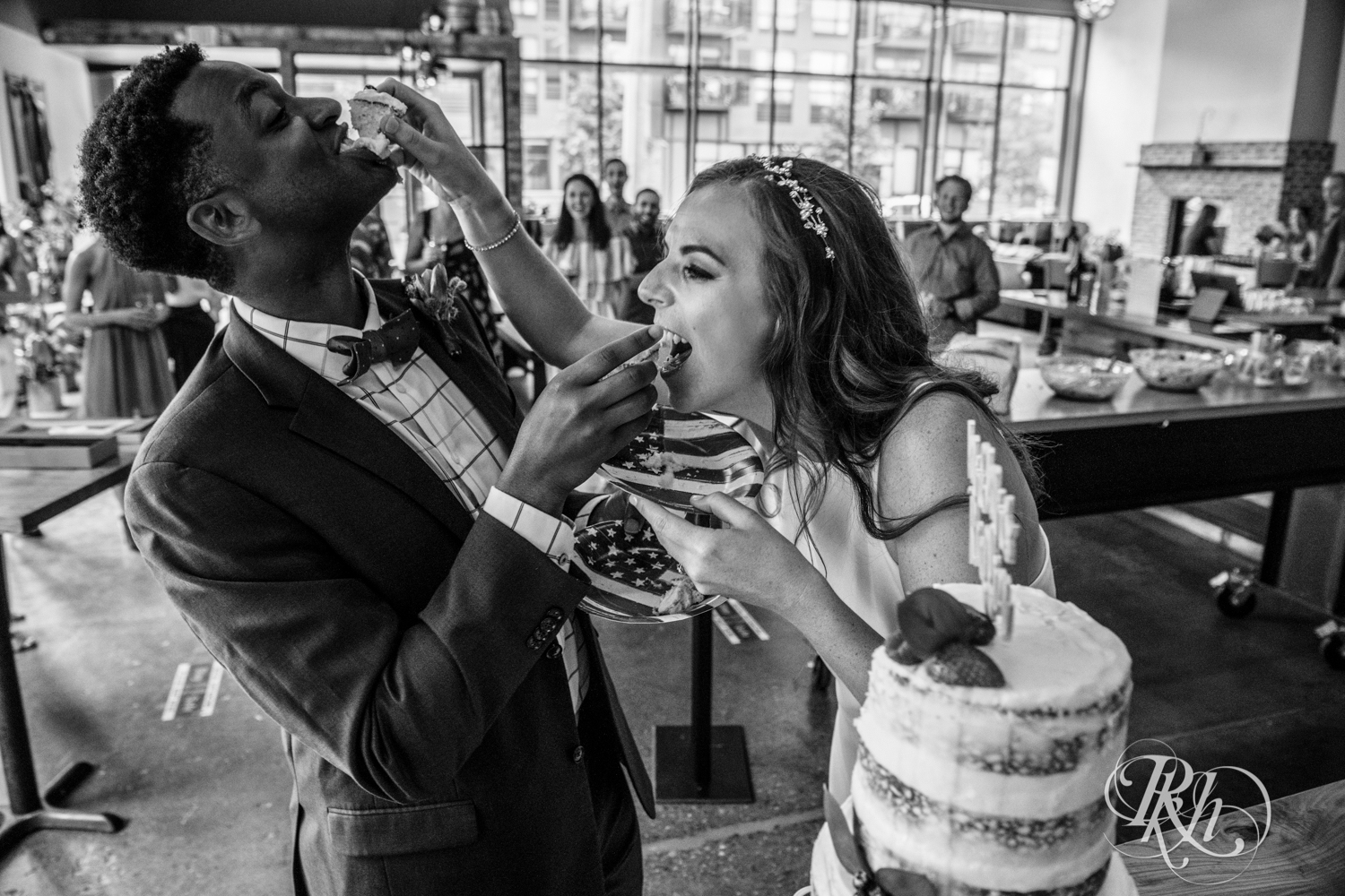 Black man and woman biracial couple eat wedding cake at wedding reception in Minneapolis, Minnesota.