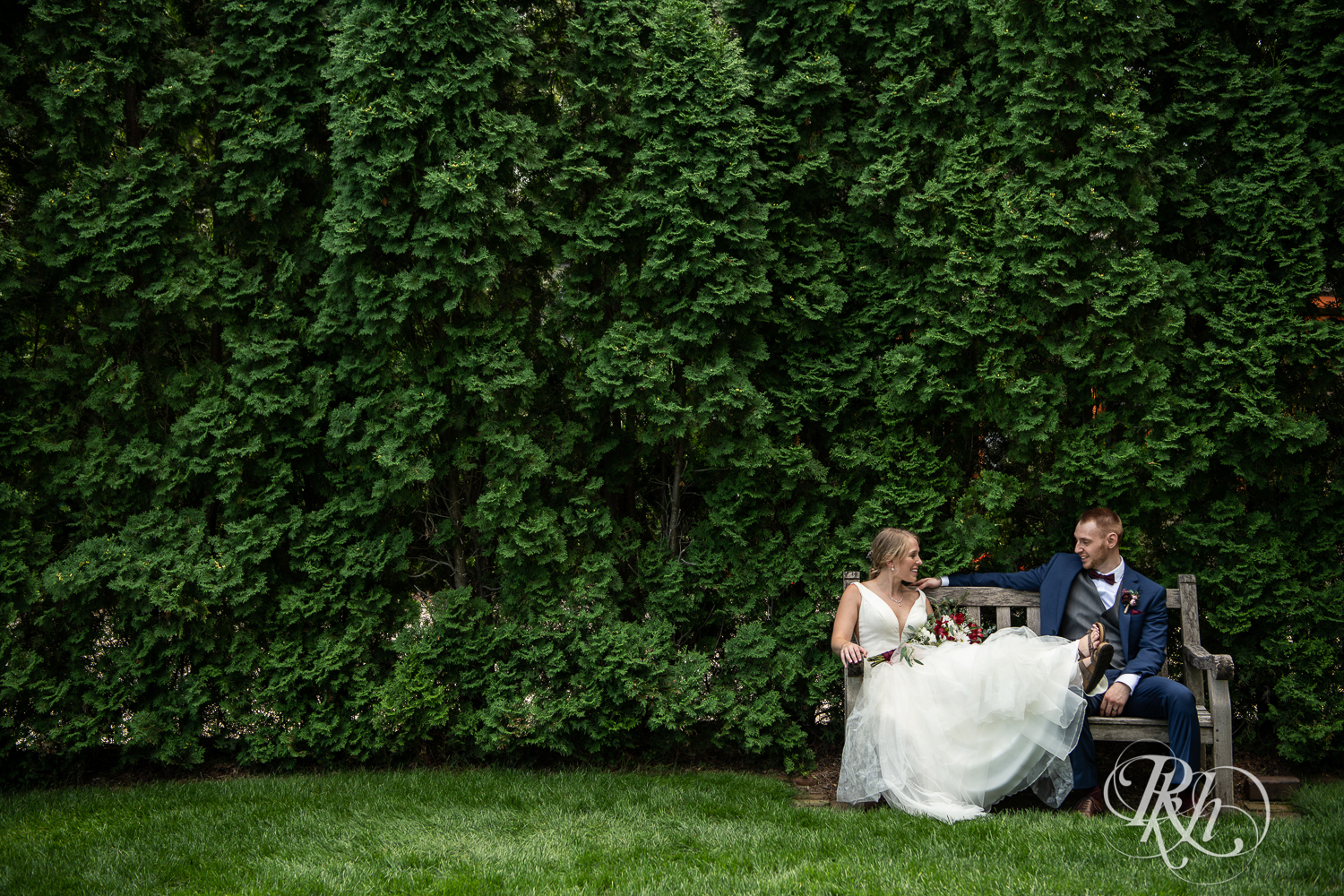 Bride and groom smile on bench at the William Sauntry Mansion in Stillwater, Minnesota.