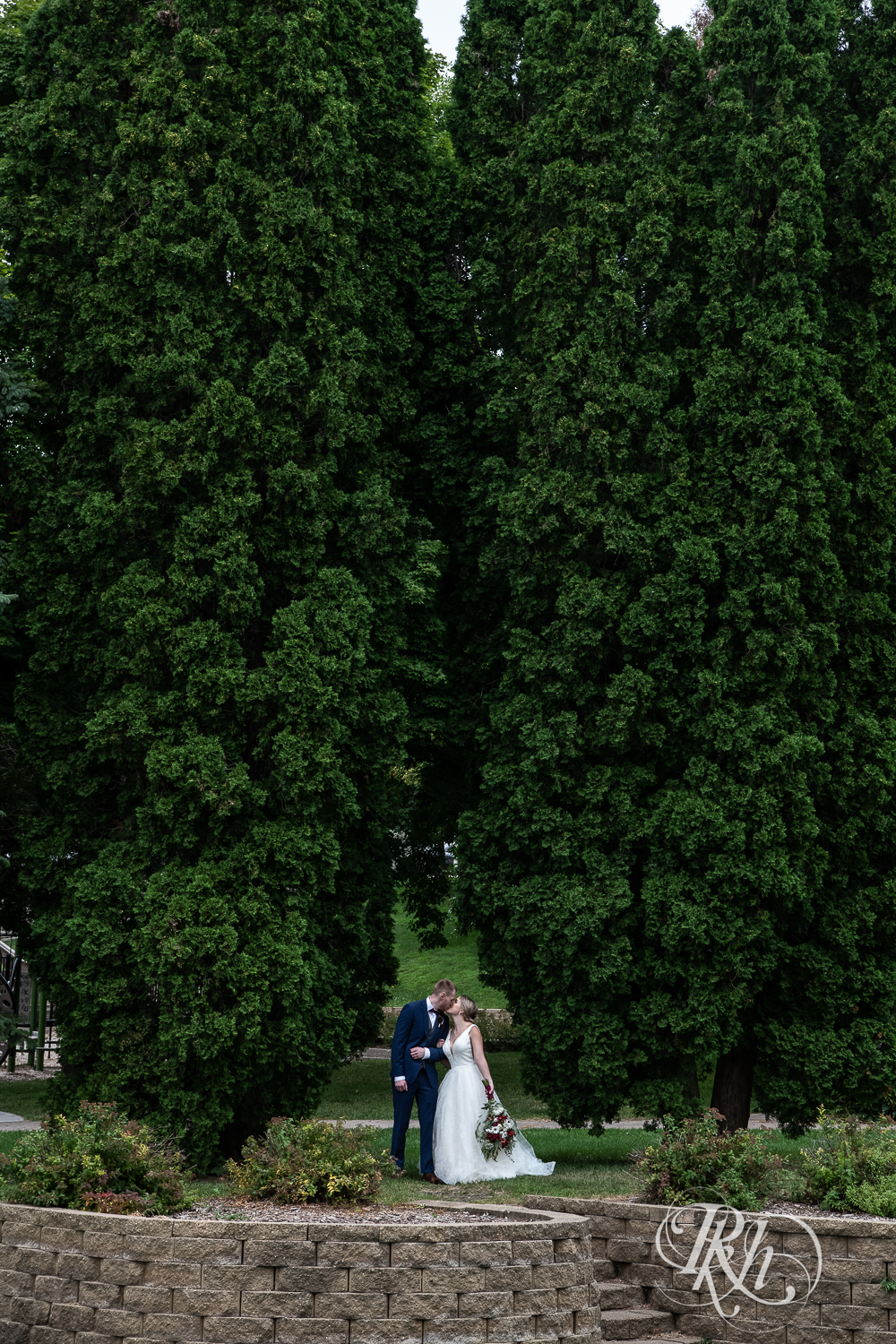 Bride and groom kiss on wedding day in Pioneer Park in Stillwater, Minnesota.