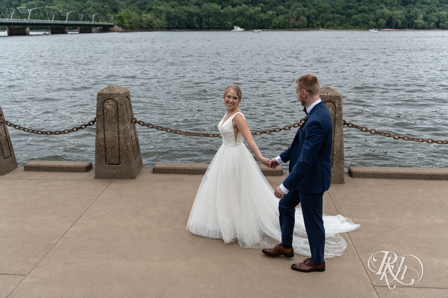 Bride and groom walk along St. Croix River in Stillwater, Minnesota.