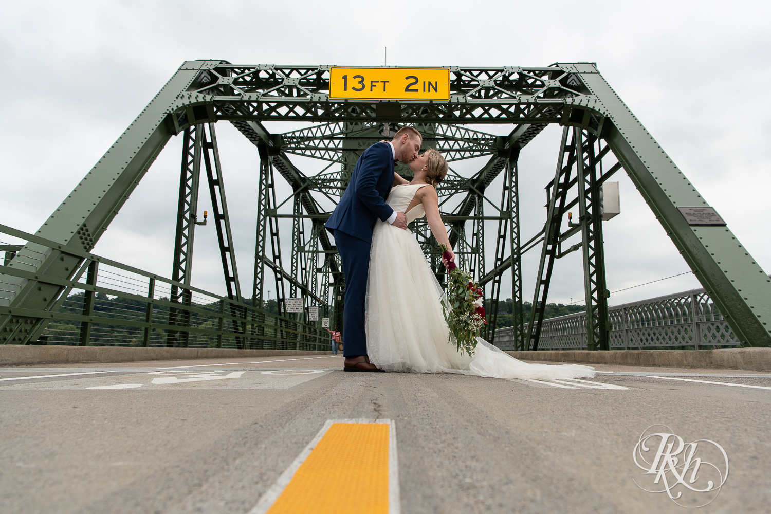Bride and groom kiss on bridge on St. Croix River in Stillwater, Minnesota.