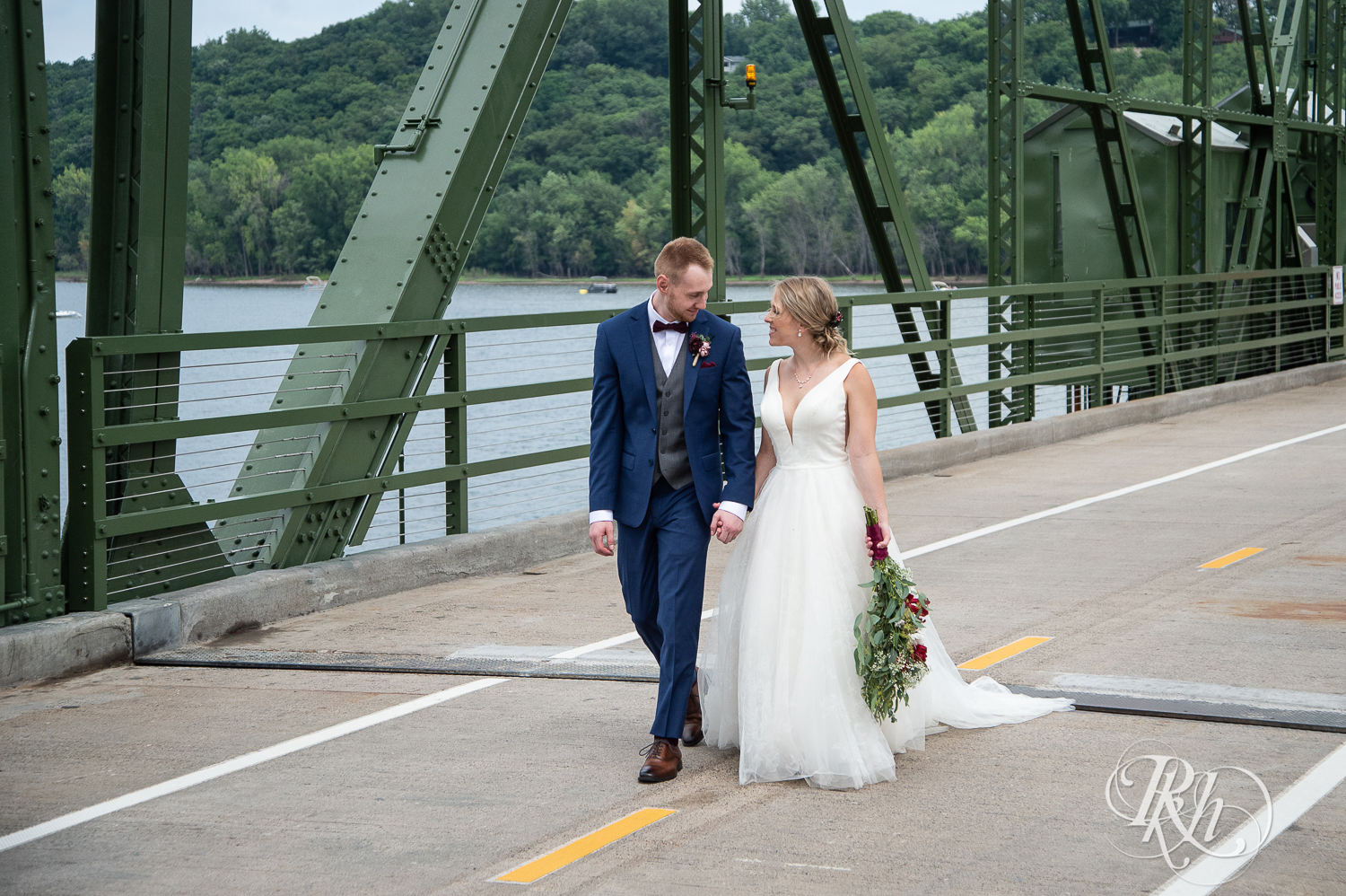 Bride and groom walk on bridge on St. Croix River in Stillwater, Minnesota.